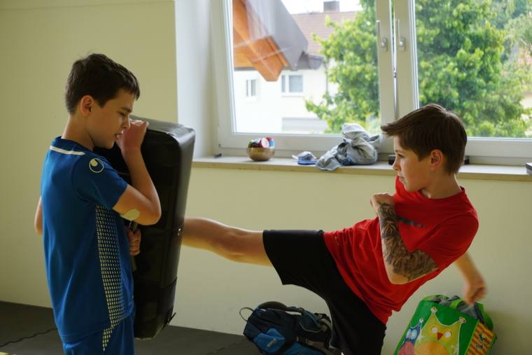 Kinder mit Boxhandschuhen schlagen Pratzen