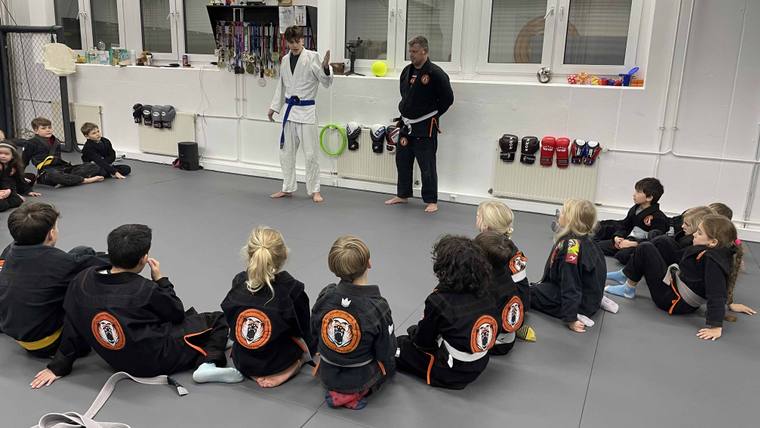 Zwei Kinder im BJJ-Gi üben eine Technik